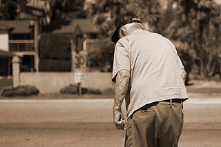 Elderly Man with a baseball cap on walking hunched over 