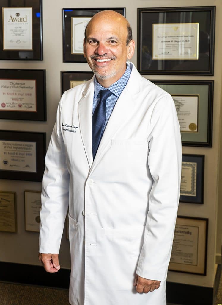 Dr. Ken Siegel standing with dental awards